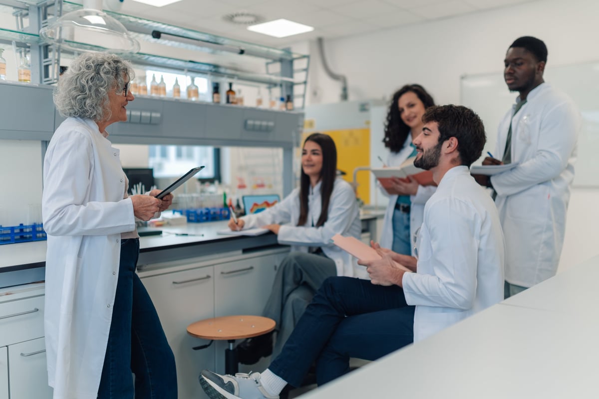 Diverse group of young adult students listening to their mature adult professor during a chemistry lecture in a lab